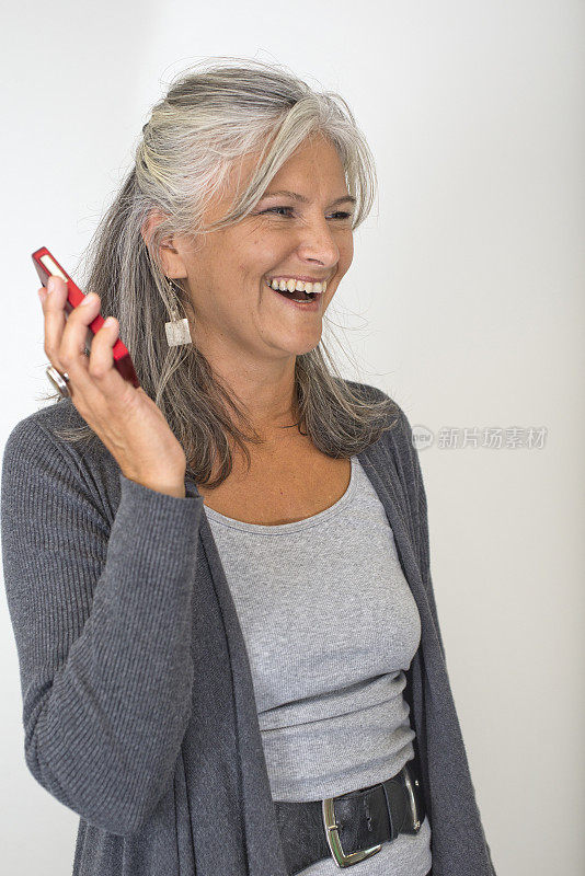 美丽成熟的女人在白色的中性背景下谈论智能手机