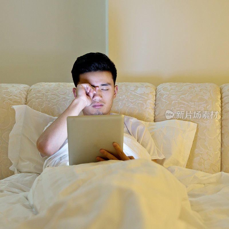 年轻人在床上用平板电脑