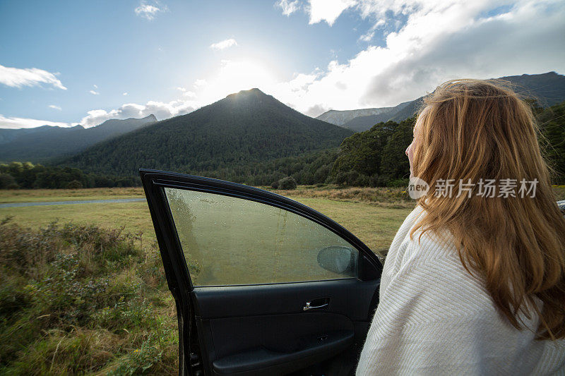 年轻女子站在车旁，看风景