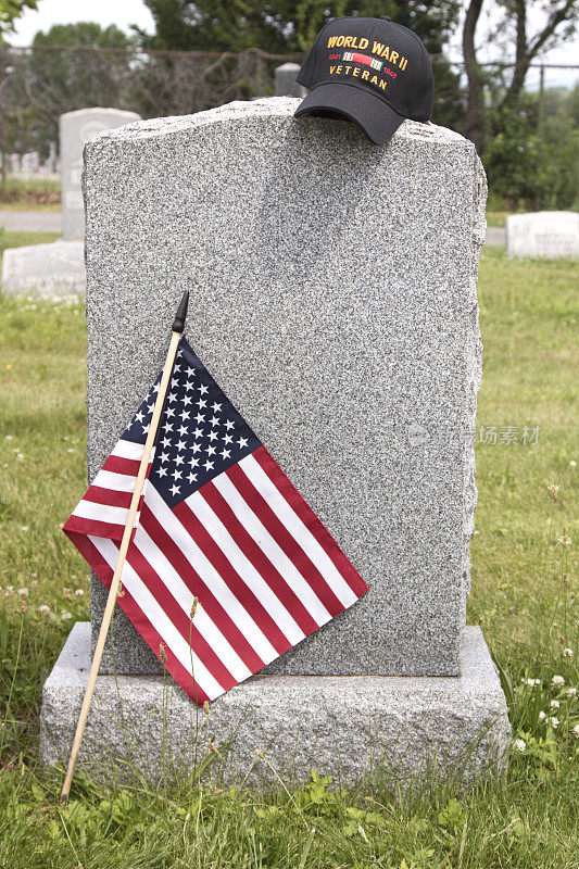 一个空白墓碑上的二战老兵的帽子，背景是墓地