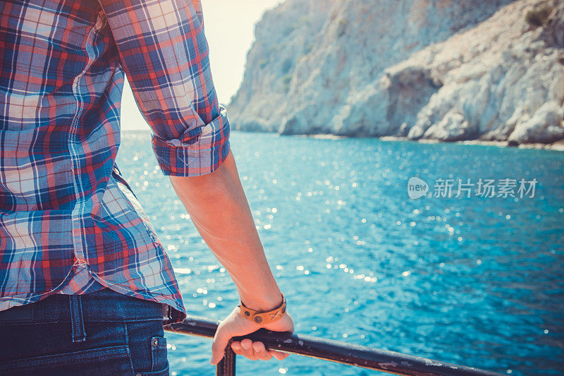 年轻人坐在一艘木制游艇上欣赏海滨景色