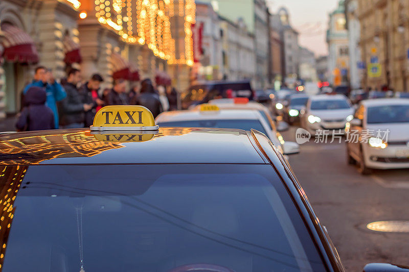 出租车到市中心的一条繁忙的街道上，车水马龙，反射在大都市的玻璃黄昏灯光