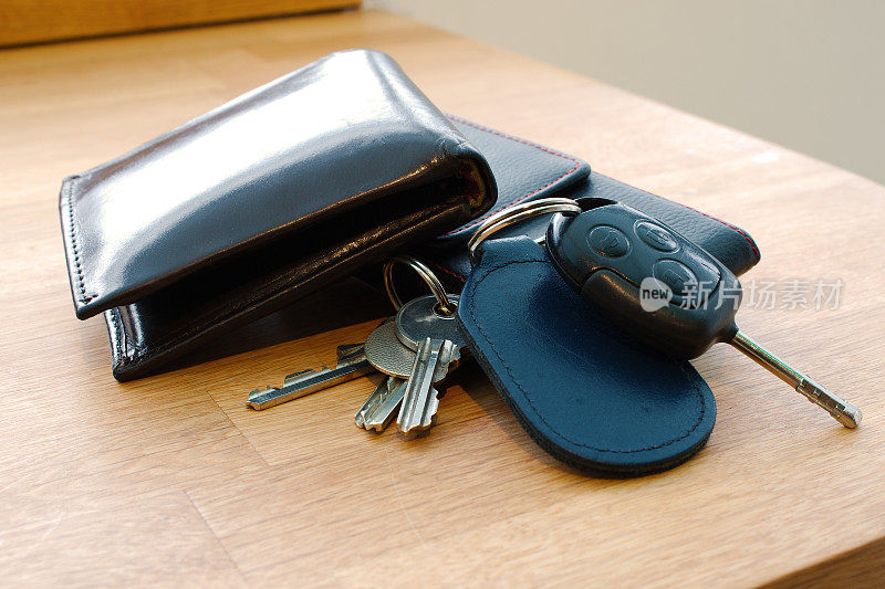 钱包，车钥匙，房间钥匙和手机放在桌子上。