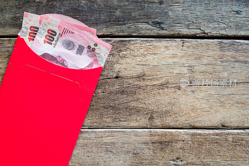 200张泰铢钞票装在红色信封里，作为春节礼物“昂包”放在木桌上
