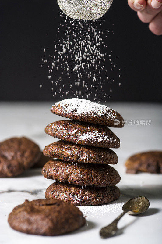 黑巧克力饼干堆在一起，在上面筛上糖粉。