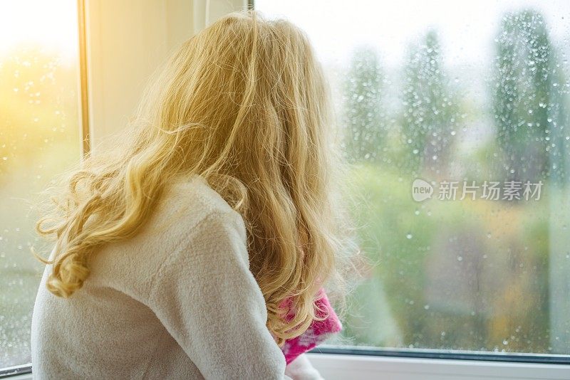 一个穿着睡衣的孩子在秋日的窗户里微笑着。