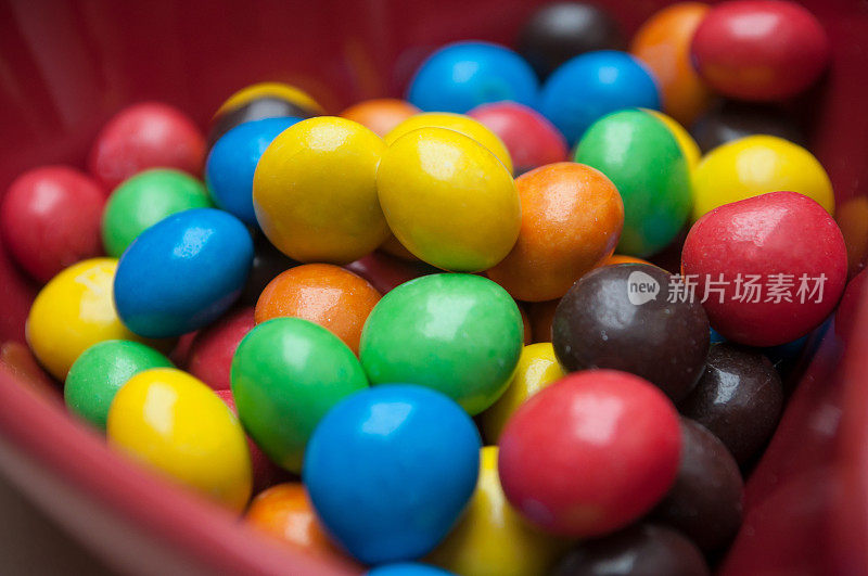 五彩缤纷的巧克力糖果放在一个红色的心形碗里