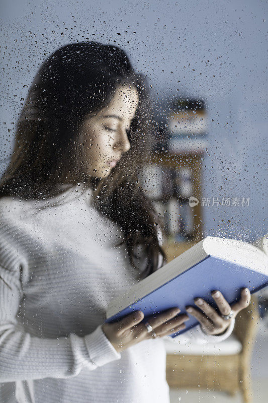 女孩躲在一扇被雨水打湿的窗户后面