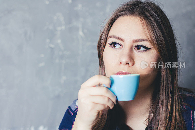 年轻的白人妇女捧着一杯咖啡享受在自由时间的肖像。