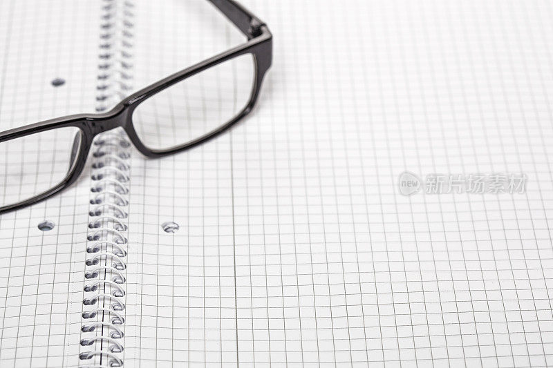 一本打开的螺旋装订的笔记本和一副眼镜