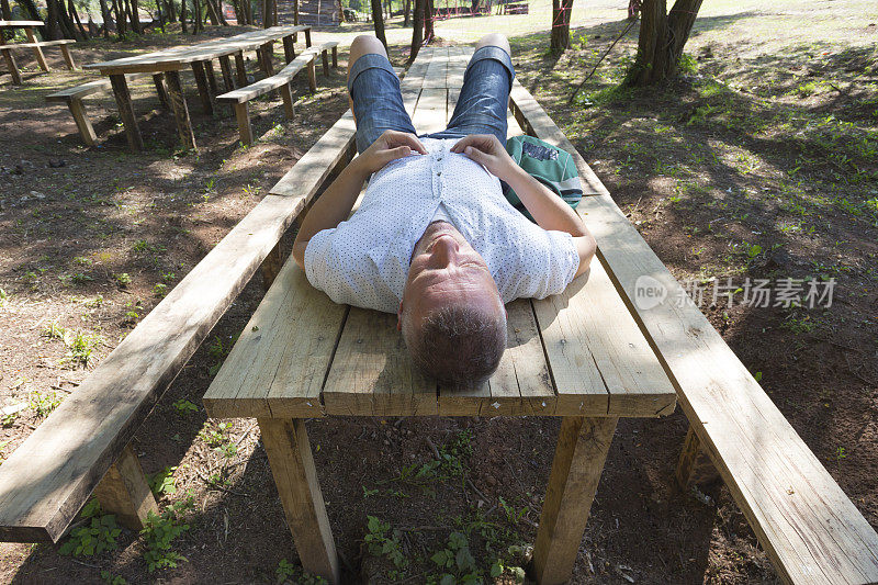 一个成年人躺在木桌上做白日梦
