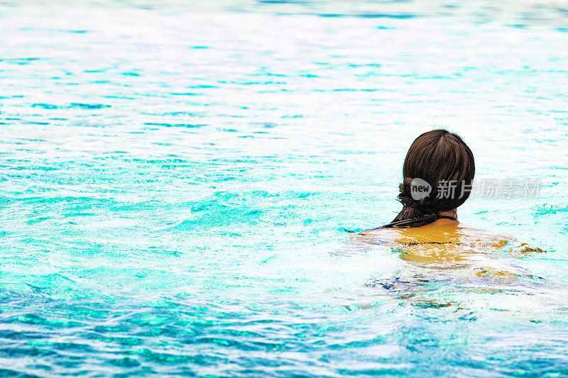 后视图的女性游泳者在水与发髻