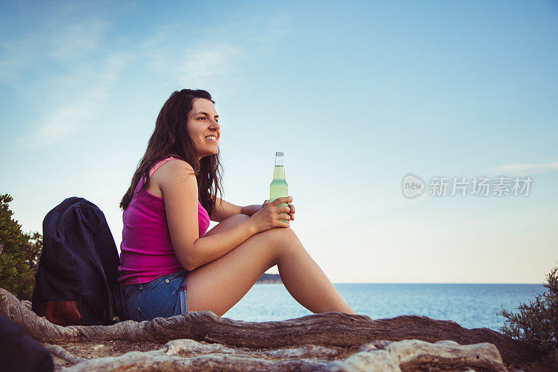 年轻女子在海边喝苏打水