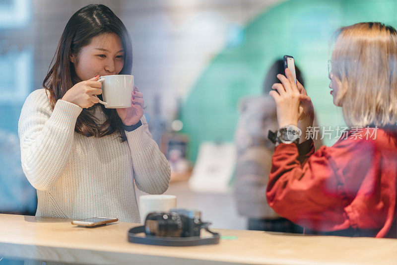 两个亚洲女性朋友正在用智能手机互相拍照
