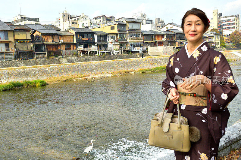 穿着和服的日本妇女在京都的秋天沿着加茂河行走