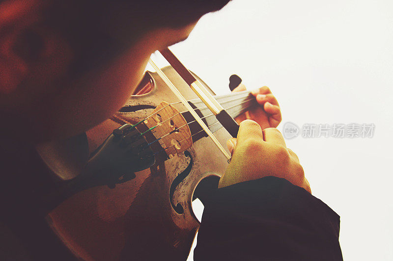 一个男孩在演奏弦乐器，小提琴