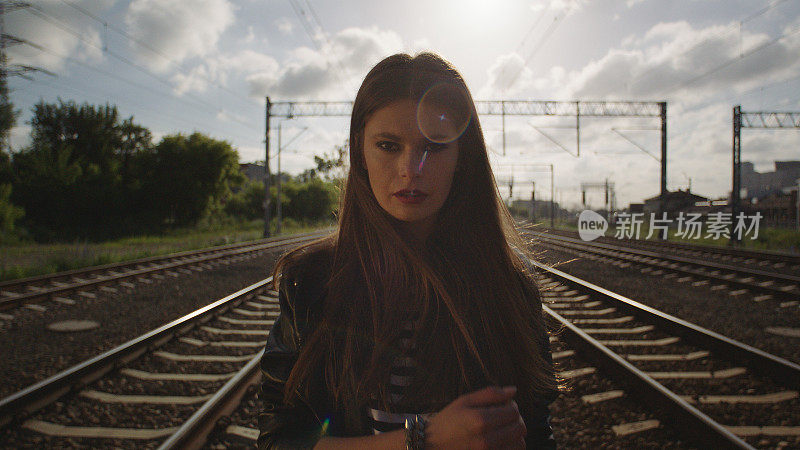 诱惑的女人走在铁路上。看相机。摇滚风格。