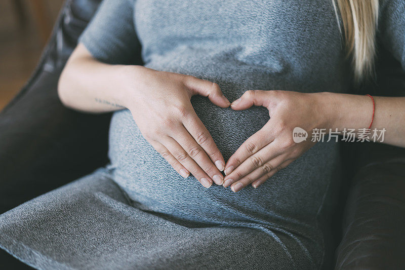 一名孕妇把手放在肚子上做心形