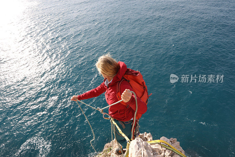 女子攀登者从岩石山顶上的海上保护