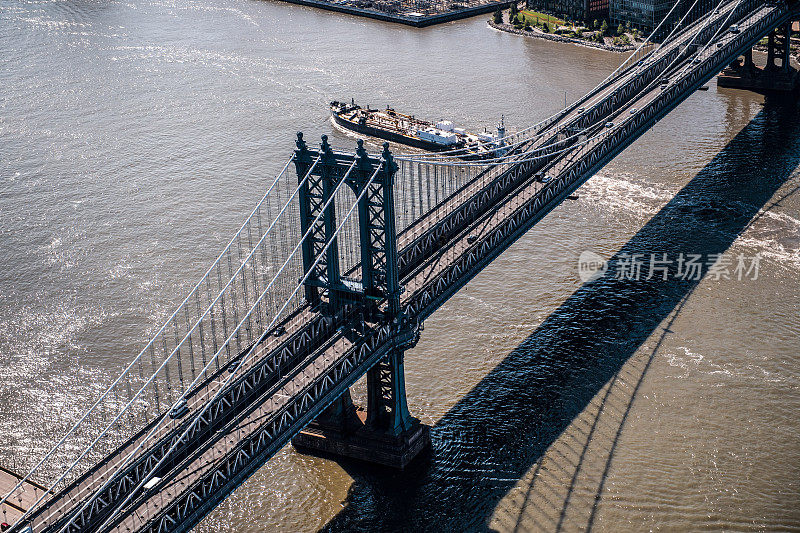 一架直升飞机拍下了纽约市曼哈顿大桥，一艘小船从桥下经过