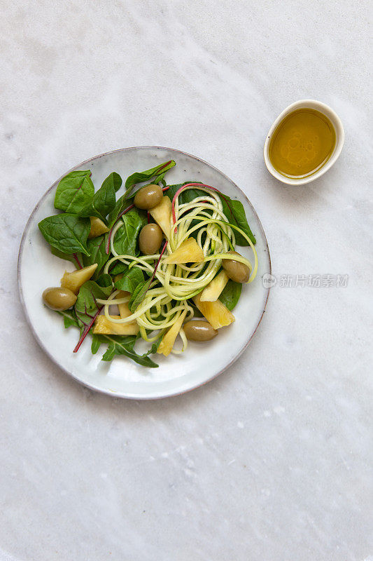 素菜沙拉配菠萝、橄榄、豆腐、西葫芦、菠菜和鹰嘴豆，在大理石背景上复制空间