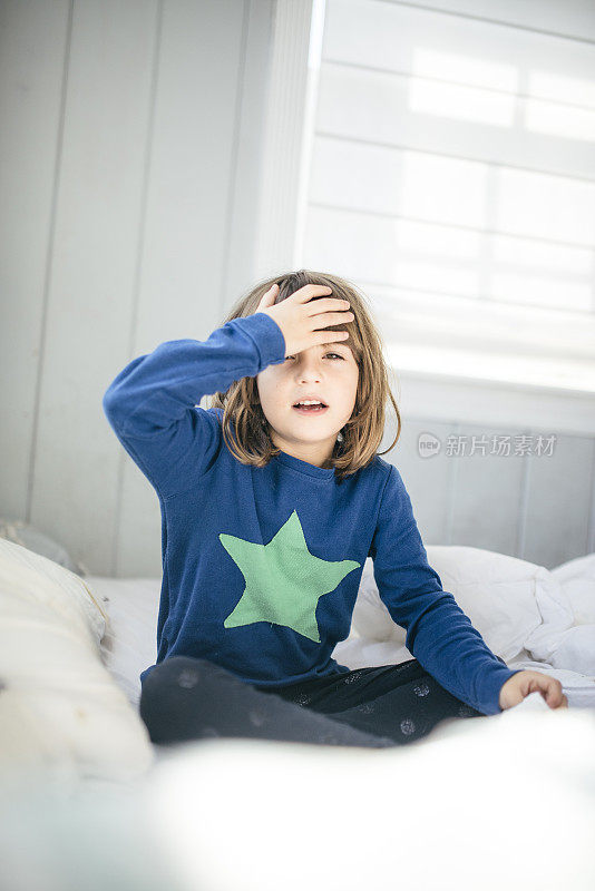 穿着睡衣的孩子躺在床上，感觉不舒服、头痛或发烧