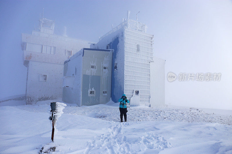 波斯尼亚和黑塞哥维那Bjelasnica山顶上，一名徒步旅行者站在被冰雪覆盖的建筑前