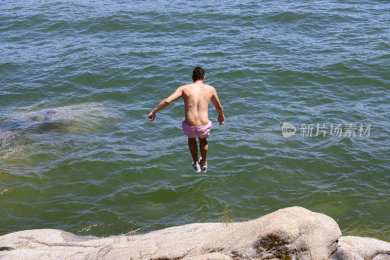 一个年轻的拉丁美洲成年人跳进湖水