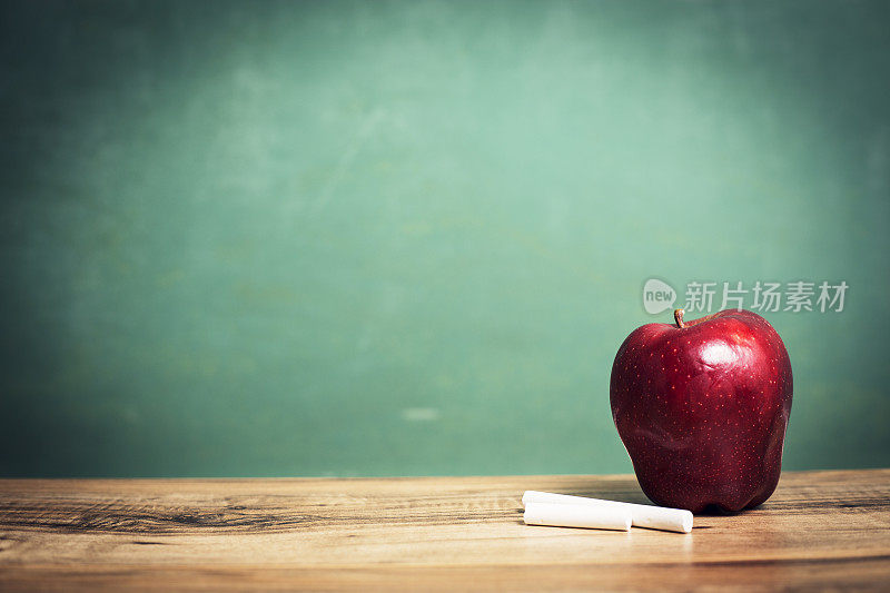 苹果，粉笔在木制课桌和黑板上。