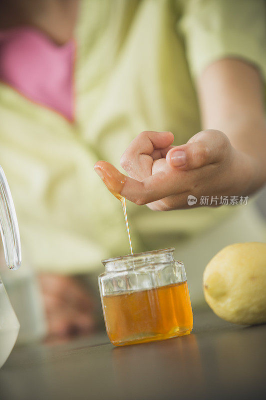 少女蘸着手指品尝蜂蜜