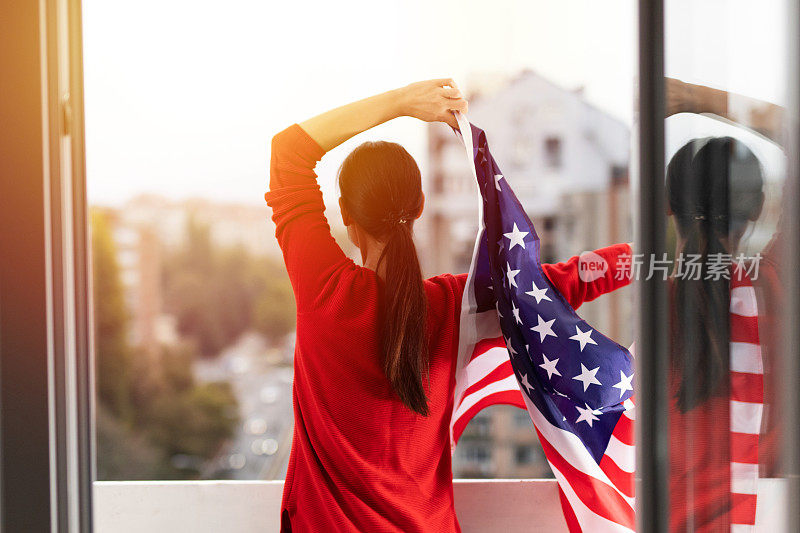 一个年轻女子在户外举着美国国旗