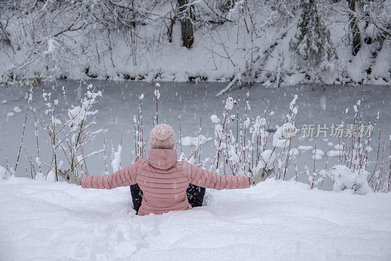 女徒步旅行者在白雪覆盖的河岸放松