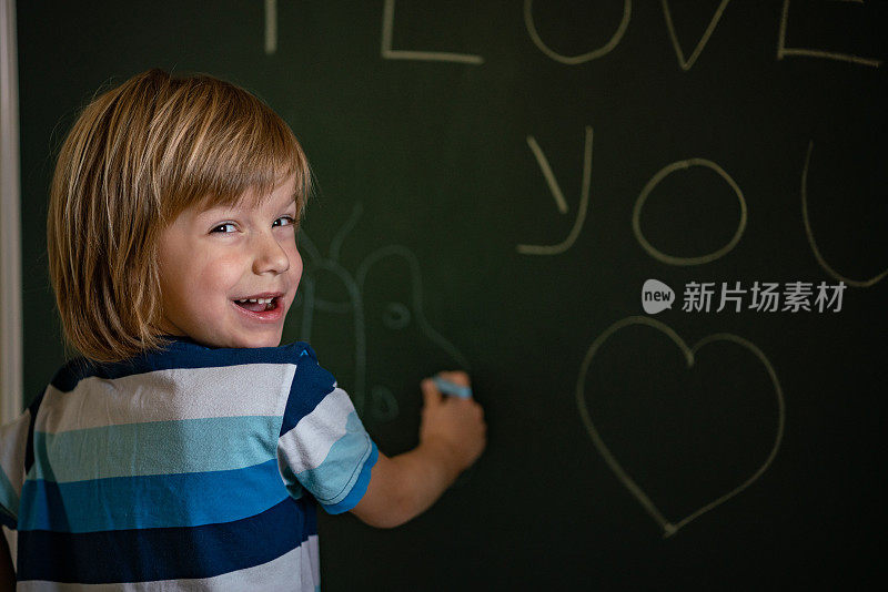 微笑的男孩在黑板上画画