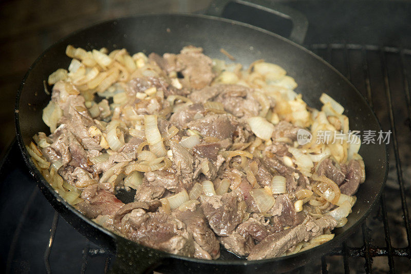 野味和洋葱在户外的铁锅里烹饪