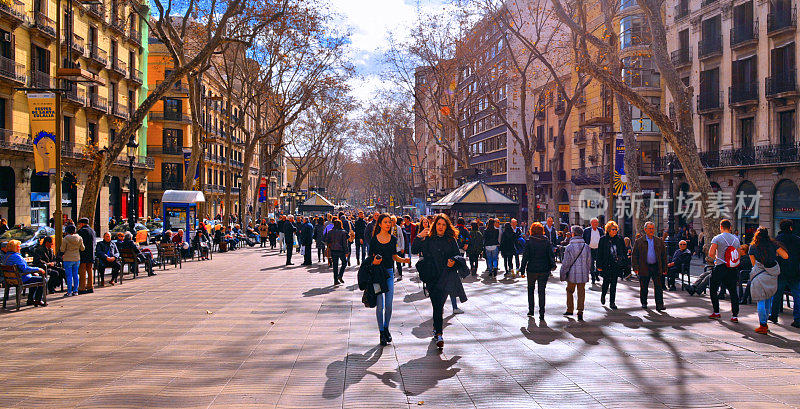 西班牙巴塞罗那，人们走过兰布拉大街的上部。