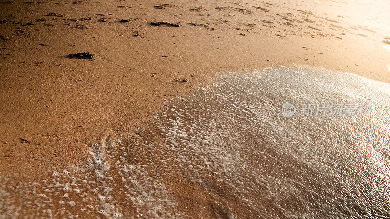 近景照片湿的沙子和脚印在海滩上在太阳送