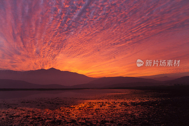 美丽的巴塔哥尼亚风景安第斯山脉与高山与发光的山峰，石头在山湖，反射，橙色红色的天空在日落