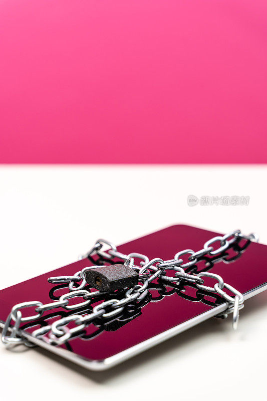 数字平板电脑与挂锁和链在粉红色的背景