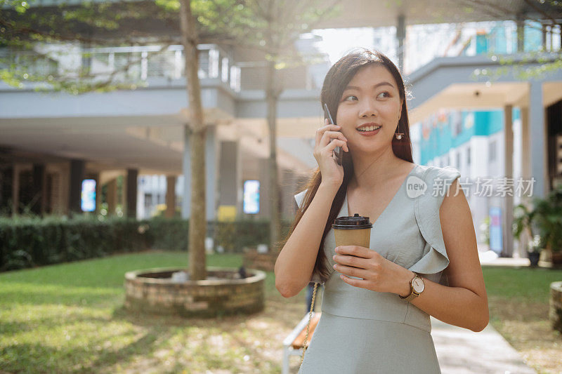 年轻时尚的亚洲女人拿着外卖咖啡和打电话