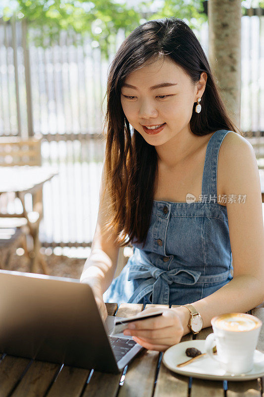 年轻的亚洲女人在网上购物的笔记本电脑