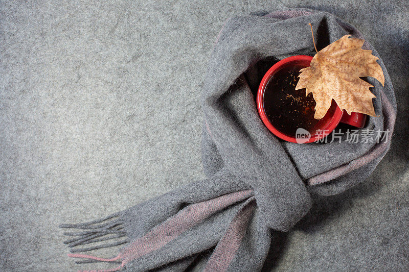 秋天的主题。红色杯子，咖啡和一条温暖的灰色围巾。