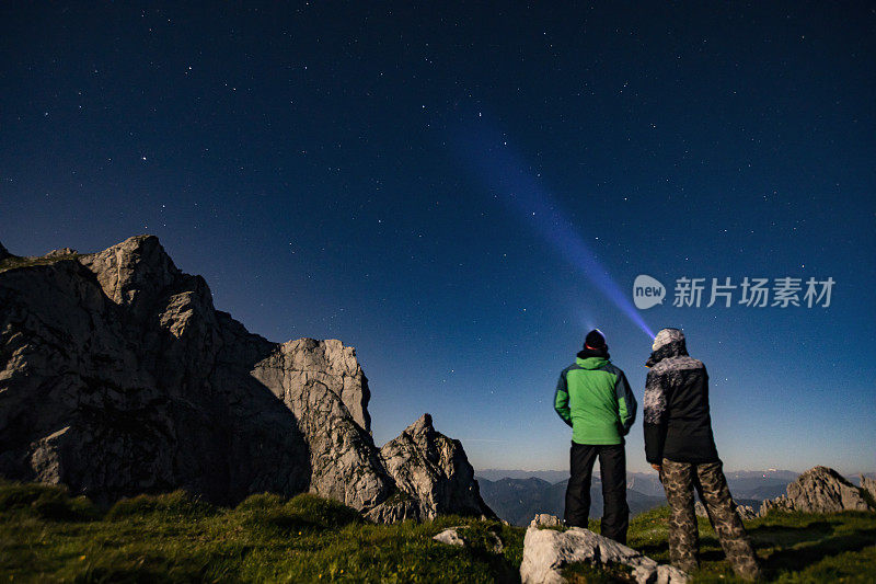 成年男性朋友在山上用车灯看夜空