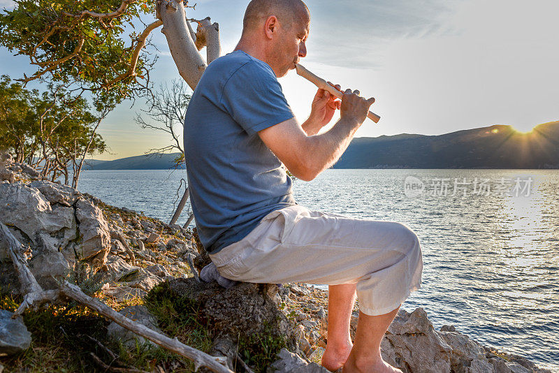 在海边，一个人吹着木笛看日落