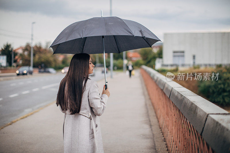 下雨天带着伞走在街上的女人