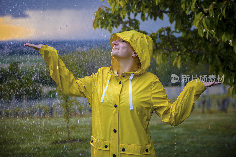 穿着黄色雨衣的快乐女人在享受雨