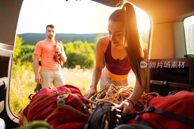 一名年轻女性登山者在男友等待时将登山装备装进背包