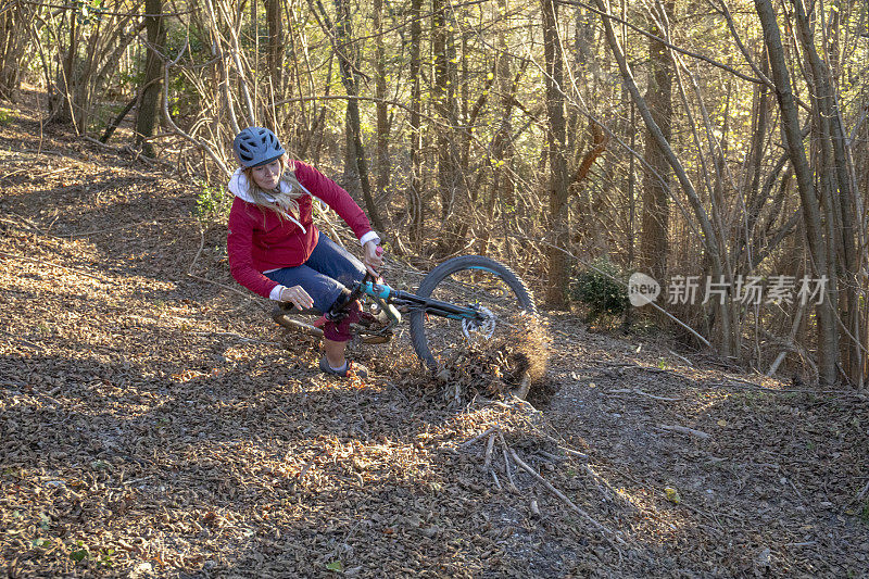 一个女山地自行车手早上在森林小径上撞车