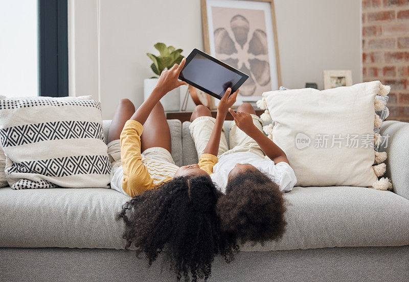 这是两姐妹在家里使用数码平板电脑的照片