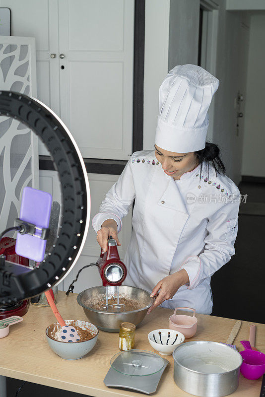 女网红厨师一边用她的光戒指和制服教她的粉丝如何制作蛋糕，一边对她的粉丝说话