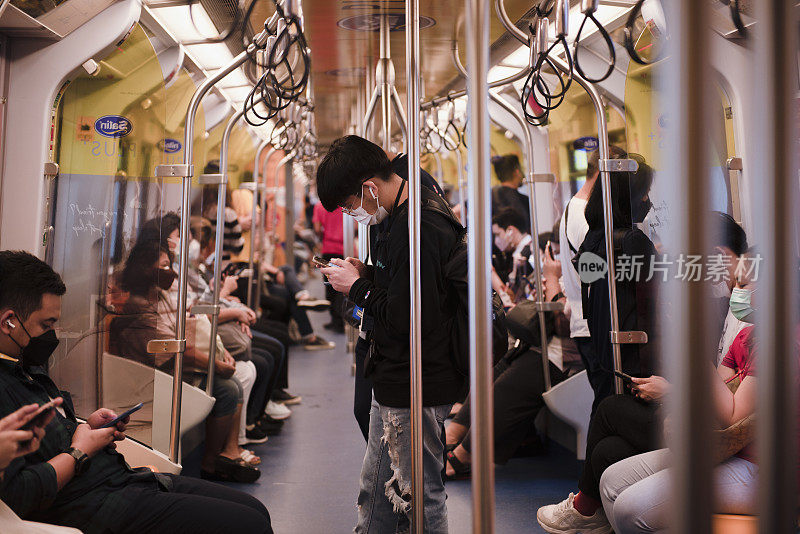 乘客在电动火车上看手机。2021年9月23日，泰国曼谷
